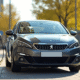 Peugeot 308 hybride en charge dans une ville ensoleillee